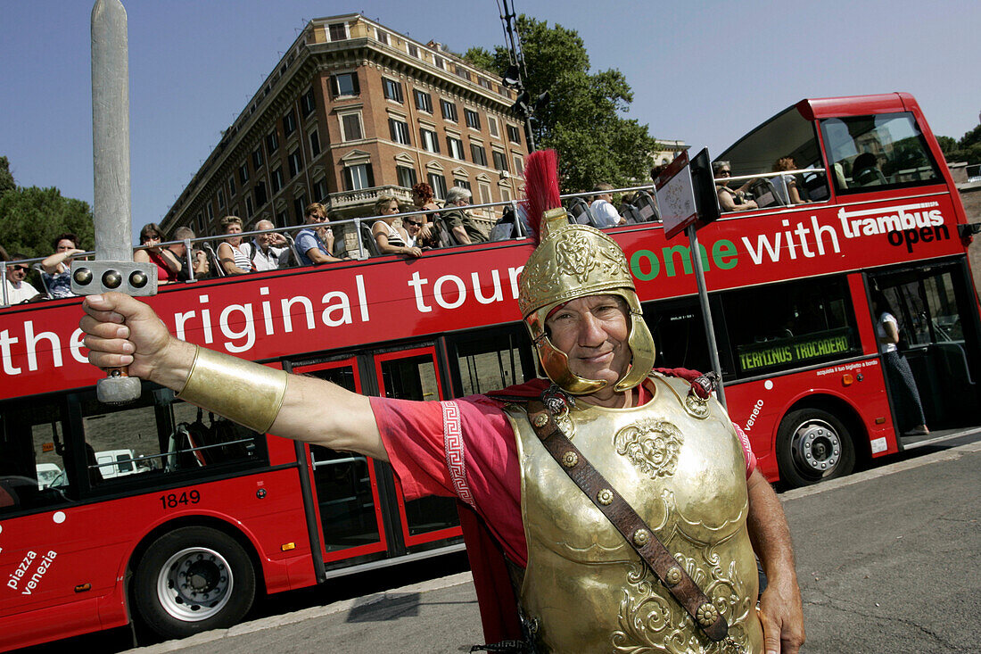 Mann im römischen Kostüm posiert für Touristen vor Besichtigungsbus beim Colosseum, Rom, Italien
