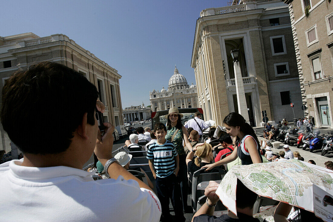 Touristen auf der obersten Plattform des Besichtigungsbusses machen Fotos vom  Petersdom, Rom, Italien