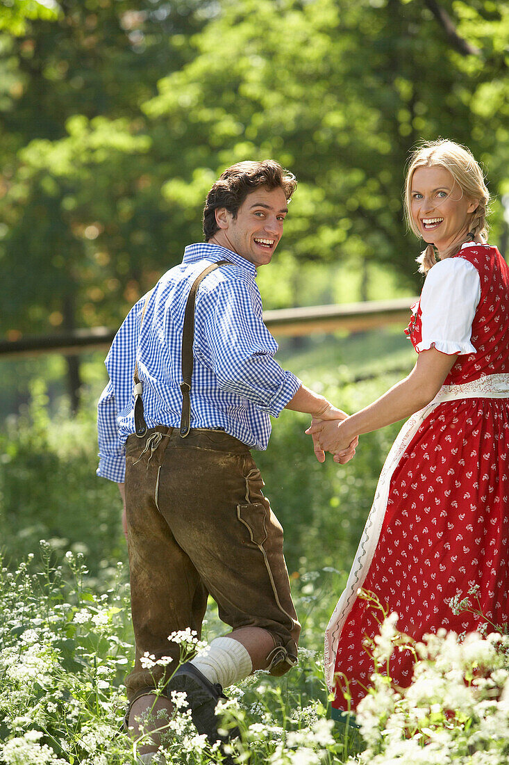 Couple running hand in hand over a meadow