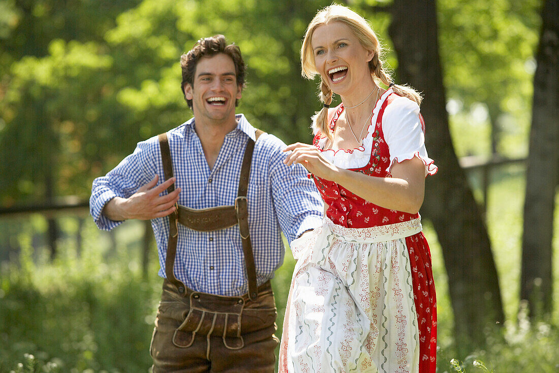 Couple running hand in hand over a meadow