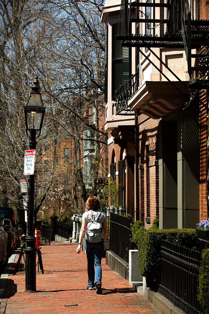 A woman walking along a street in Historic Beacon Hill, Boston, Massachusetts, USA