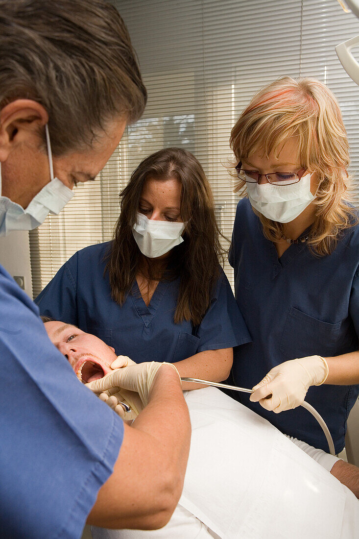 Zahnbehandlung, Zahnbehandlung beim Zahnarzt, Zahnarzt und Helferin beugen sich über den Patienten. Praxis Dr. Vesic, Hannover