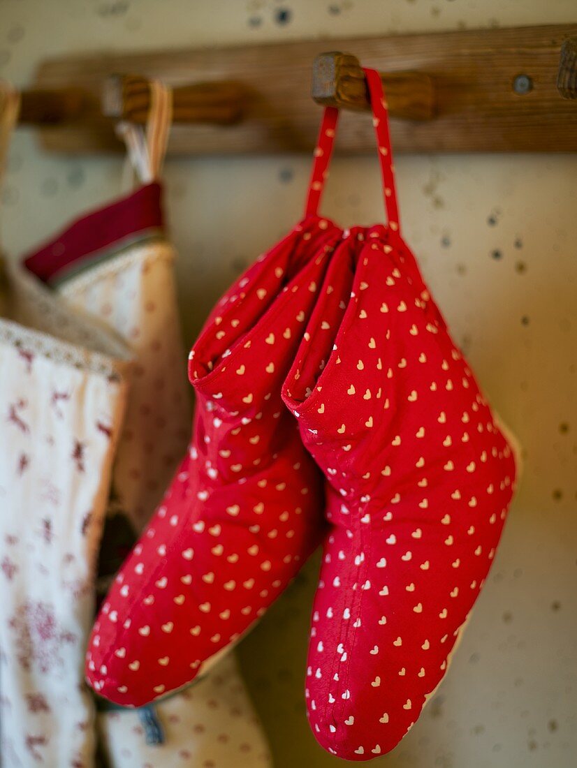 Red slippers made from fabric with a heart print on wardrobe hooks