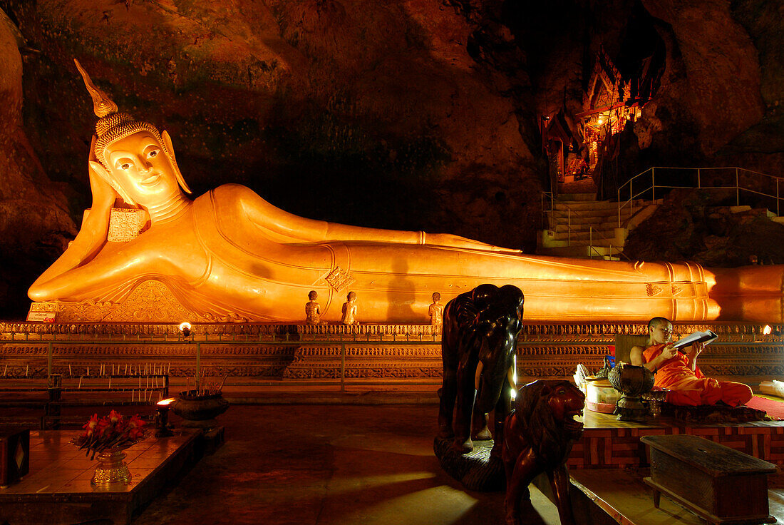Lying Buddha and buddhist monk in the Tham Yai cave near cloister Wat Suwan Kuha, Phang Nga, Thailand