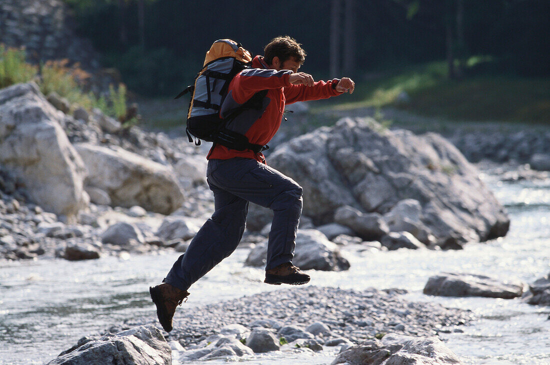 Man jumping over a creek, Upper Loisach, Garmisch-Partenkirchen, Bavaria, Germany