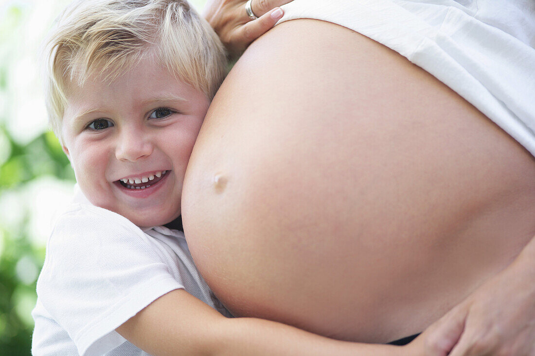 Junge (4-5 Jahre) umarmt Babybauch seiner Mutter, Steiermark, Österreich