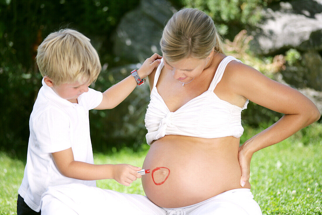 Junge (4-5 Jahre) malt Kreis auf Bauch einer schwangeren Frau, Steiermark, Österreich