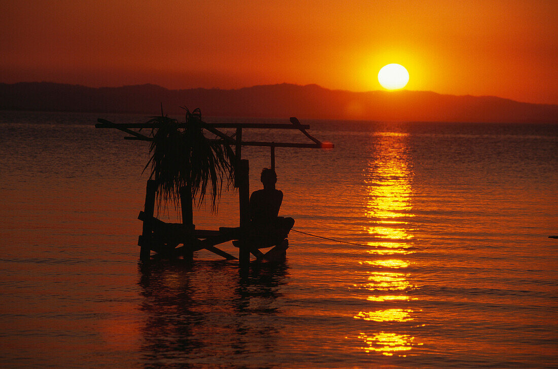 Fisherman sitting on a wooden platform at sunset, Moyagalpa, Isla de Ometepe, Lake Nicaragua, Nicaragua