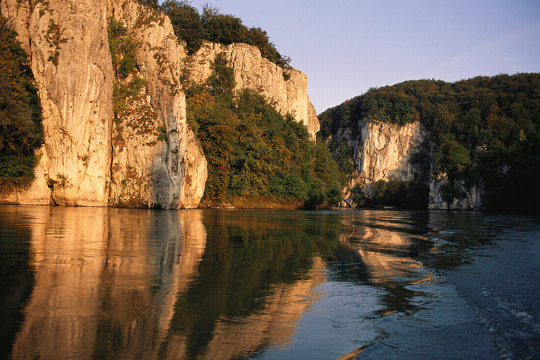 Sonnenbeschienene Kalksteinklippen spiegeln sich in der Donau, Niederbayern, Bayern, Deutschland