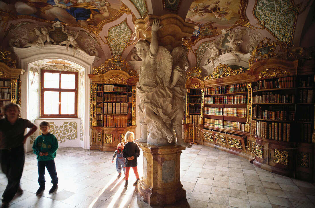 Kinder bestaunen die Figuren an einem Gewölbepfeiler in der barocken Bibliothek der Benediktinerabtei Metten, Niederbayern, Bayern, Deutschland