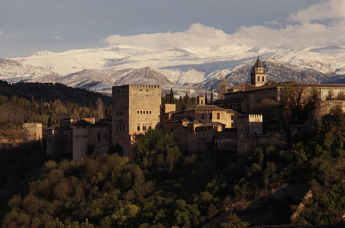 The Alhambra, Moorish palace in front of snow covered mountain range Sierra Nevada, Granada, Andalusia, Spain