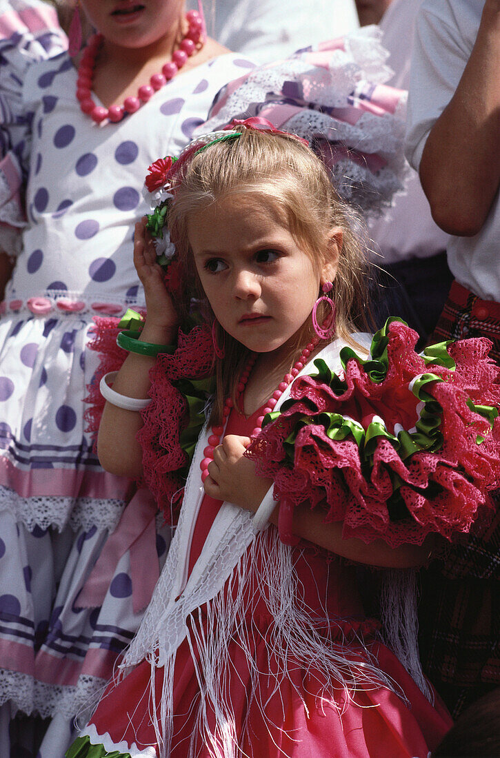 Kleines Mädchen in einem bunten Rüschenkleid beim Fronleichnamsfest, Granada, Andalusien. Spanien