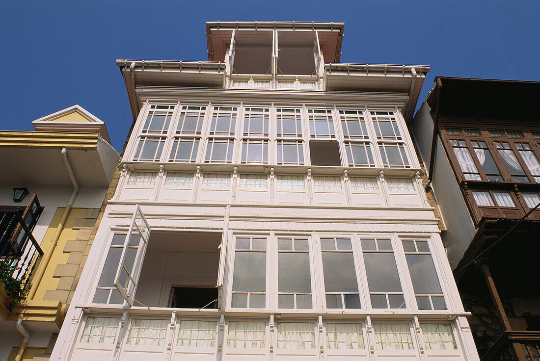 Glazed white wooden balconies at the facade of a traditional house in Comillas, Cantabria, Spain