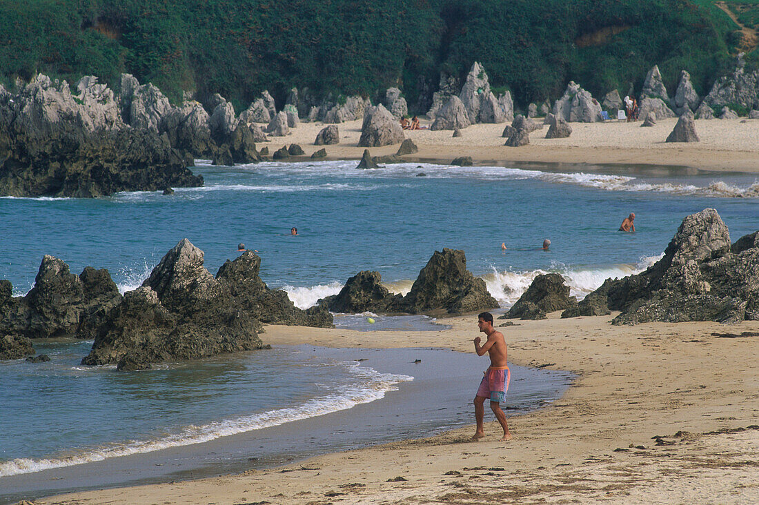 Spitze Felszähne und badende Menschen am Sandstrand Playa de Toró in Llanes, Asturien, Asturias, Costa Verde, Golf von Biskaya, Spanien