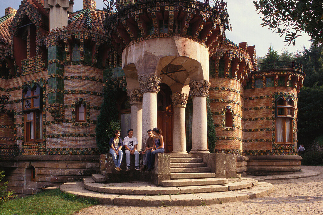 Young people sitting at the portico of Villa El Capricho, Comillas, Cantabria, Spain