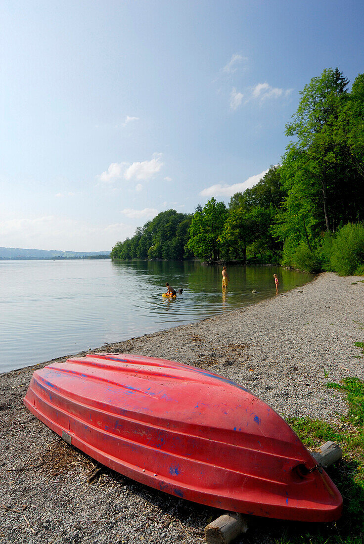 Red boat at shore of lake Kochelsee with family in background, Upper Bavaria, Bavaria, Germany