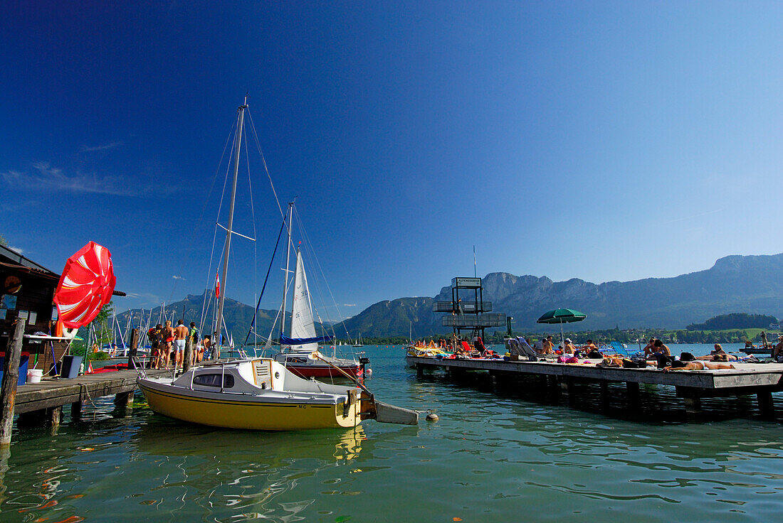 Landing stage with sailing boats and bathers at lake Mondsee, Salzkammergut, Upper Austria, Austria