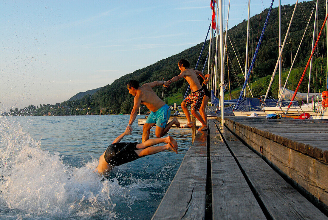 Junge Männer springen vom Bootssteg, Attersee, Salzkammergut, Salzburg, Österreich