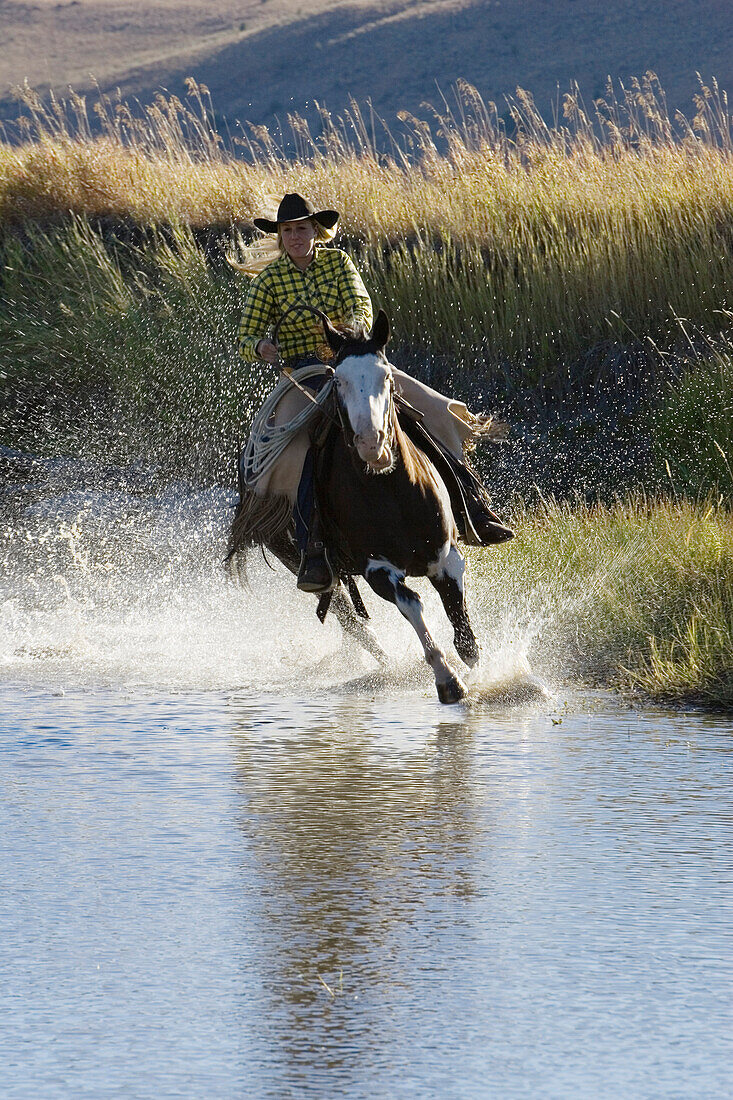 Cowgirl reitet in Bachbett, Wilder Westen, Oregon, USA