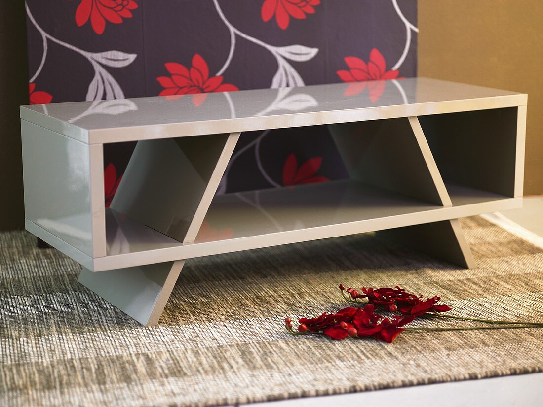 Flowers and book shelf in front of black wallpaper with a floral pattern