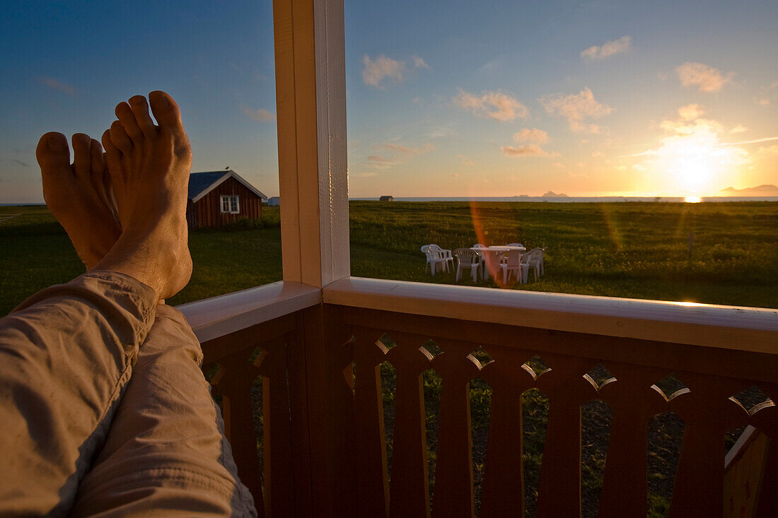 Midnight sun shining on bare feet on a veranda, Hadselsand, Austvagoya Island, Lofoten, Norway