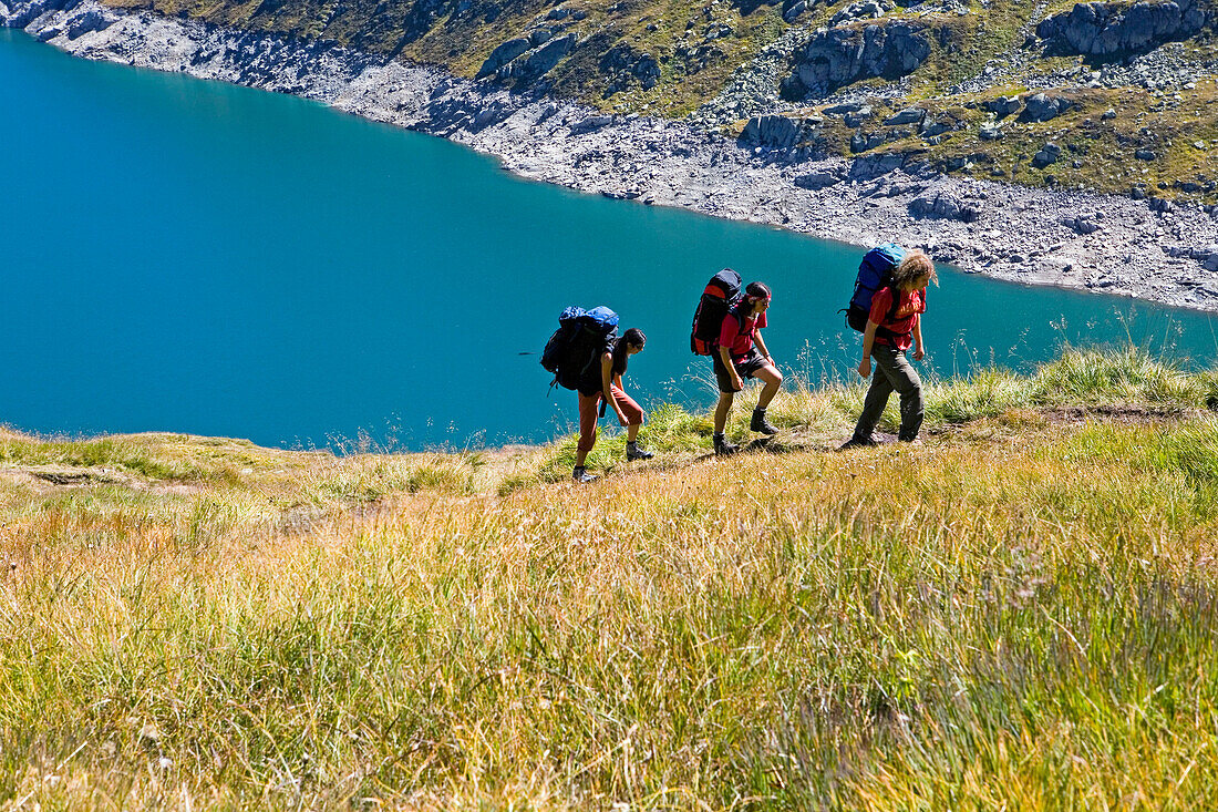 Three young people hiking, reservoir Lago di Lucendro, Gotthard, Canton of Ticino, Switzerland