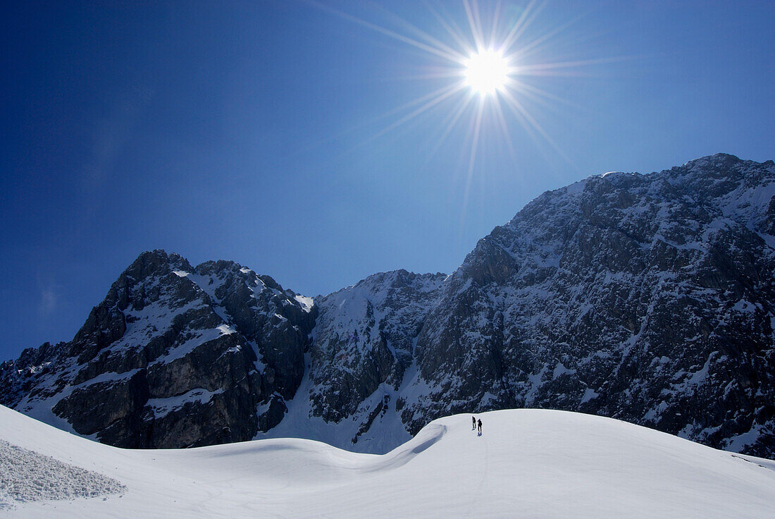 Two back-country skiiers on snow cornice with Heiterwand in background, Tschachaun, Lechtal Alps, Vorarlberg, Austria