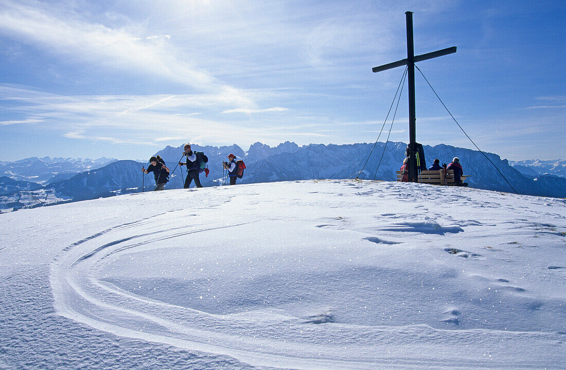 Group of hikers at summit cross, mount Wandberg with view to Wilder and Zahmer Kaiser range, Chiemgau Alps, Upper Bavaria, Bavaria, Germany