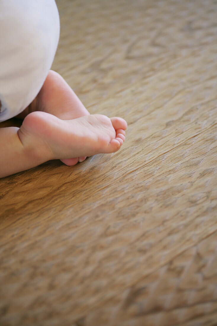 Baby hockt auf dem Fußboden, Nahaufnahme Füße