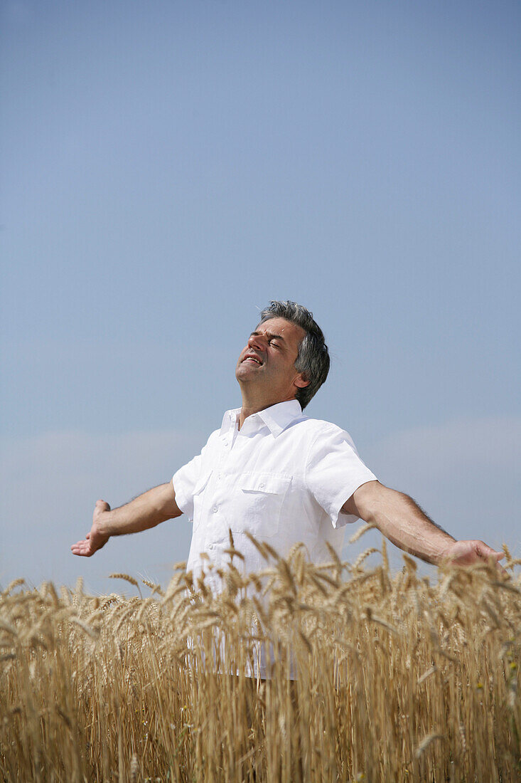 Man with outstreched arms standing in a corn field, Carinthia, Austria