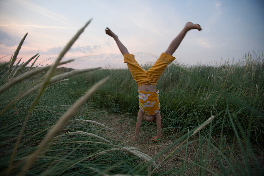 Junges Mädchen schlägt Rad durch Dünen, Henne Strand, Jütland, Dänemark, Europa
