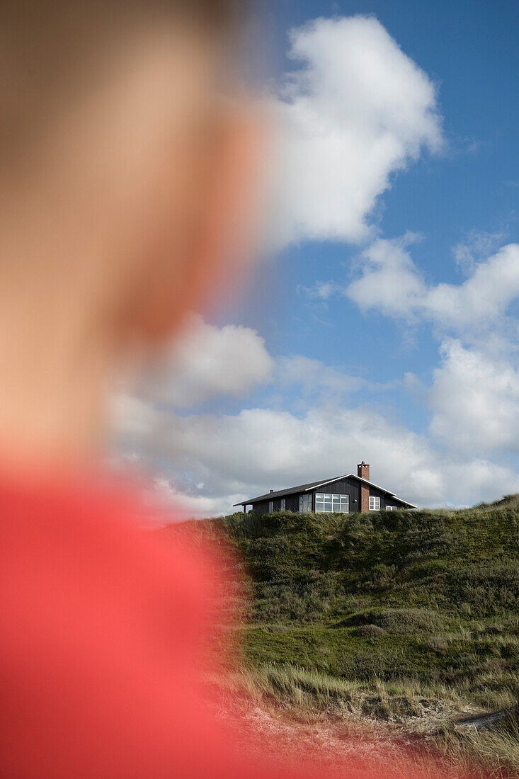 Junges Mädchen blickt auf Ferienhaus in Dünen, Henne Strand, Jütland, Dänemark, Europa