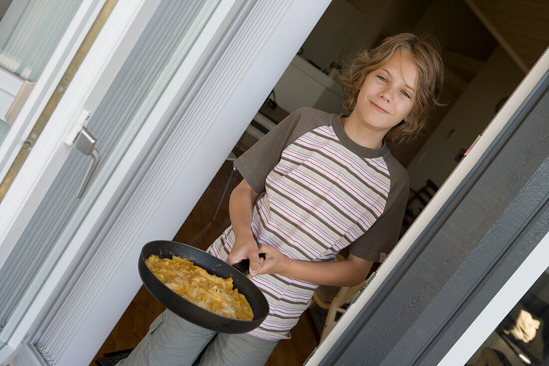 Boy holding a pan with scrambled eggs, Sylt island, Schleswig-Holstein, Germany