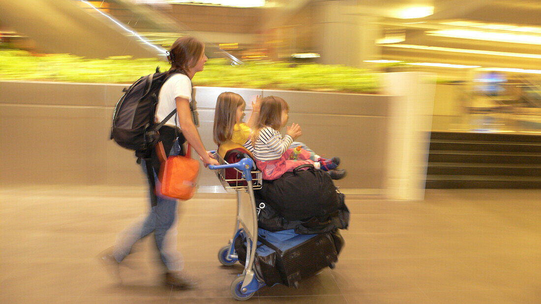 Mutter mit zwei klatschenden Töchtern, Gepäckwagen der Familie, Flug nach Neuseeland mit Singapore Airlines, Stop-over in Singapur, Flughafen, Changi Airport, Singapur