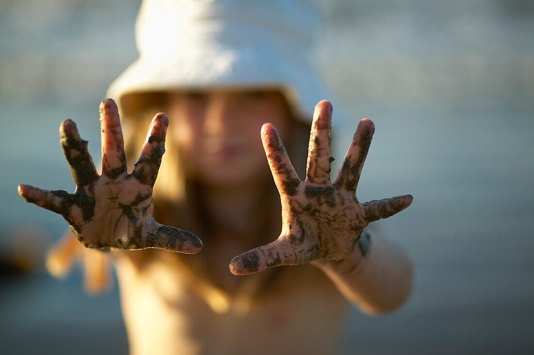 Girl (4-5 years) showing muddy hands, Spiekeroog island, East Frisian Islands, Lower Saxony, Germany
