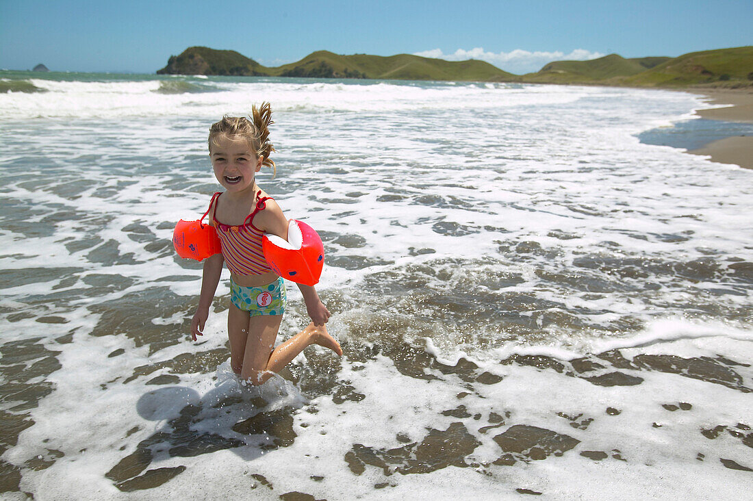 Girl (5y.) running in shallow water, campground on the beach, Port Jackson on the northern tip of Coromandel Peninsula, North Island, New Zealand