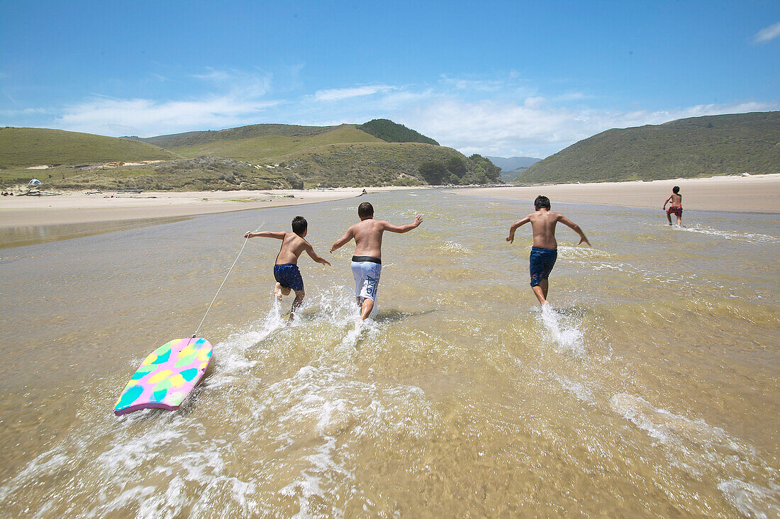 Maori Jungen spielen in Fluß, an Westküste: Waimamaku Beach, Flußlauf ins Meer, bei Opononi / Omapere, Northland, Nordinsel, Neuseeland