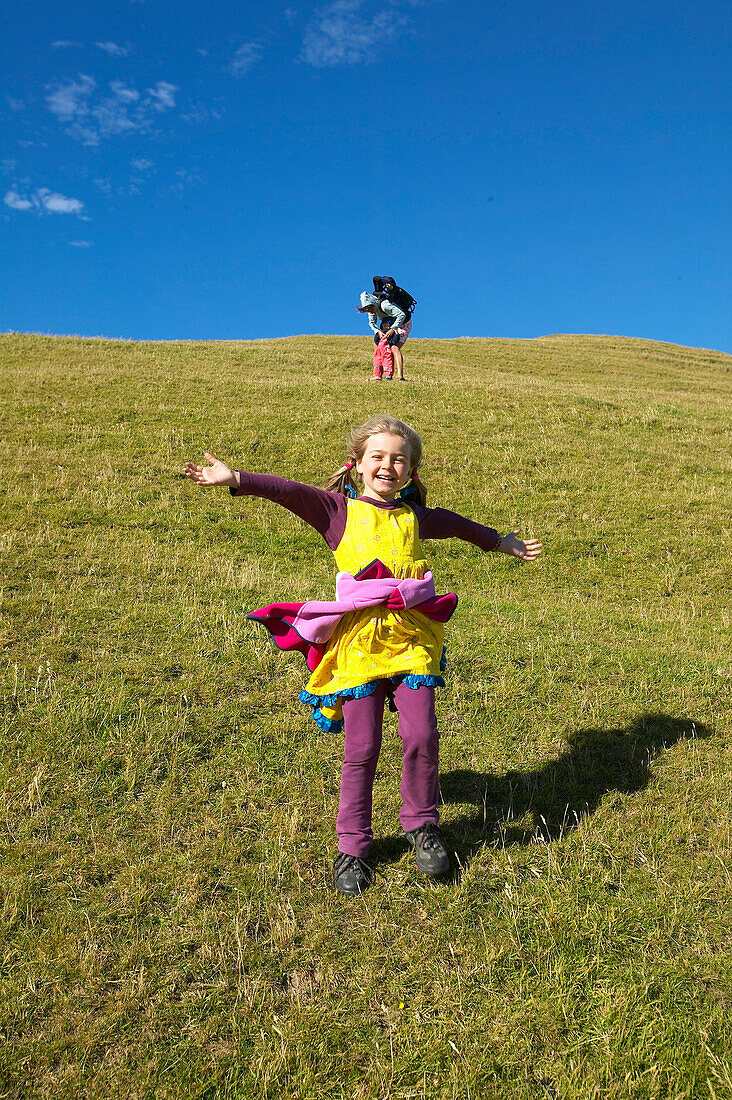 Girl running on farmland, grazing sheep, near Puponga, Golden Bay, northern coast of South Island, New Zealand