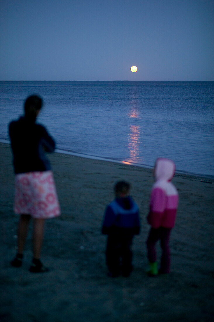 Mother and children at the beach, full moon rising over Golden Bay, northern coast of South Island, New Zealand