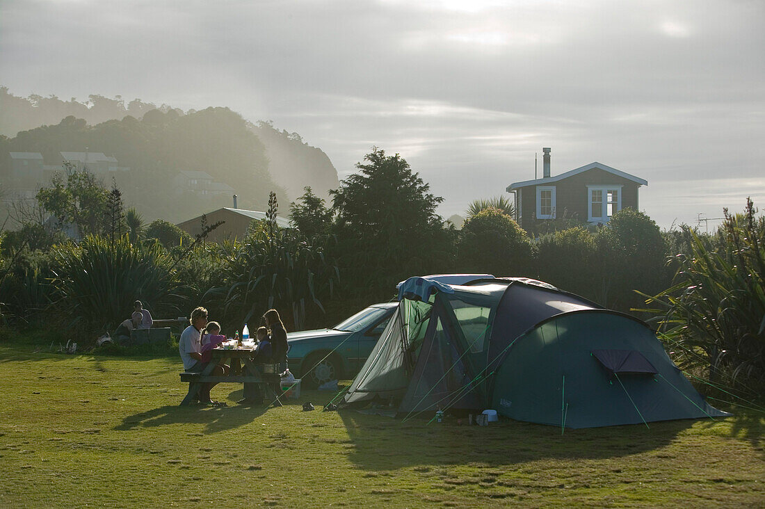 Campground dinner in front of family tent, next to beach, Okarito, at Westland National Park, Westcoast, South Island, New Zealand