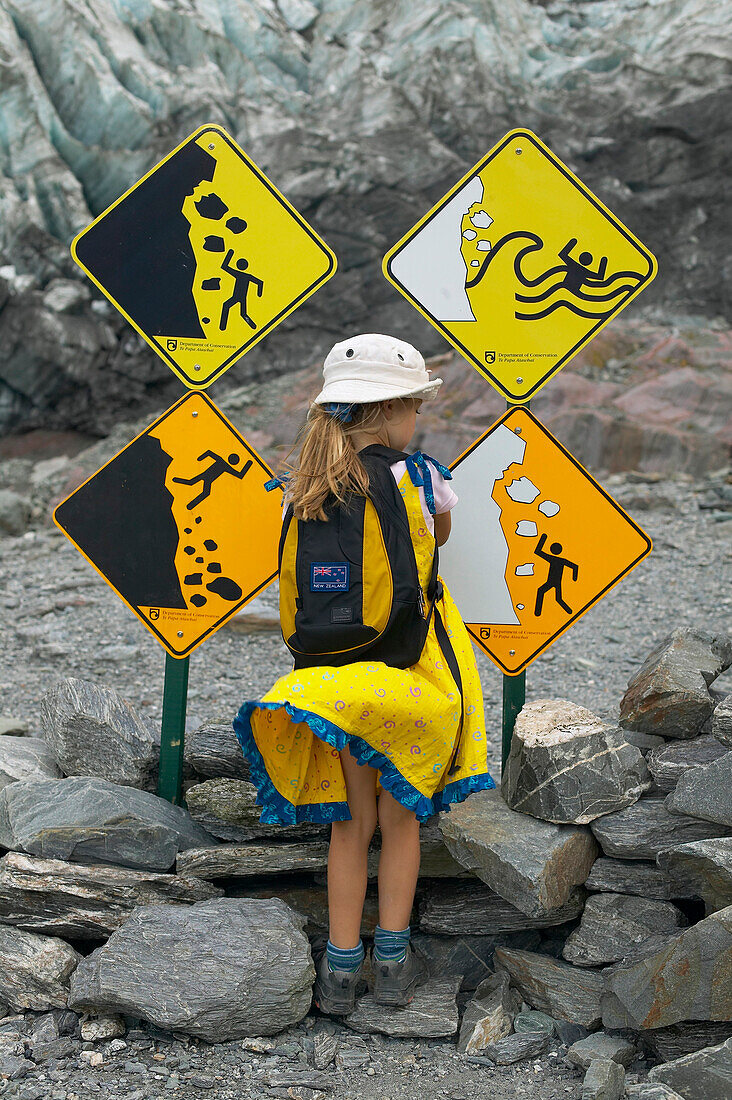 Girl watching warning signs, hiking at Franz Josef Glacier, Westland National Park, Westcoast, South Island, New Zealand