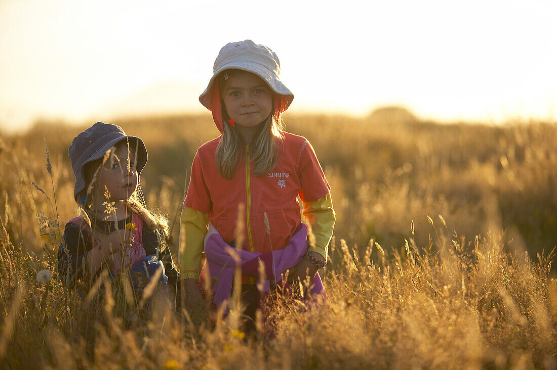 Kinder laufen durch hohes Gras, Sonnenuntergang an der Westküste, bei Haast, Südinsel, Neuseeland