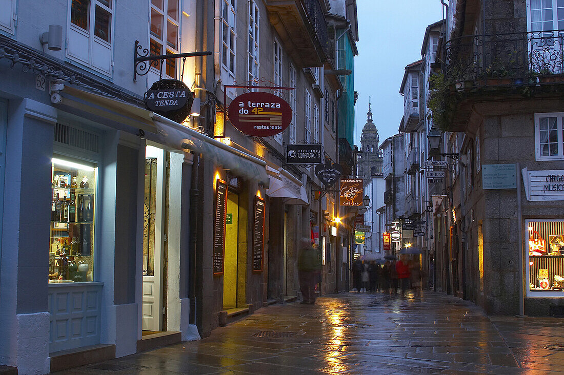 An alley in the old part of the town in the evening with clock tower in the background, Torre del Reloj, Santiago de Compostela, Galicia, Spain