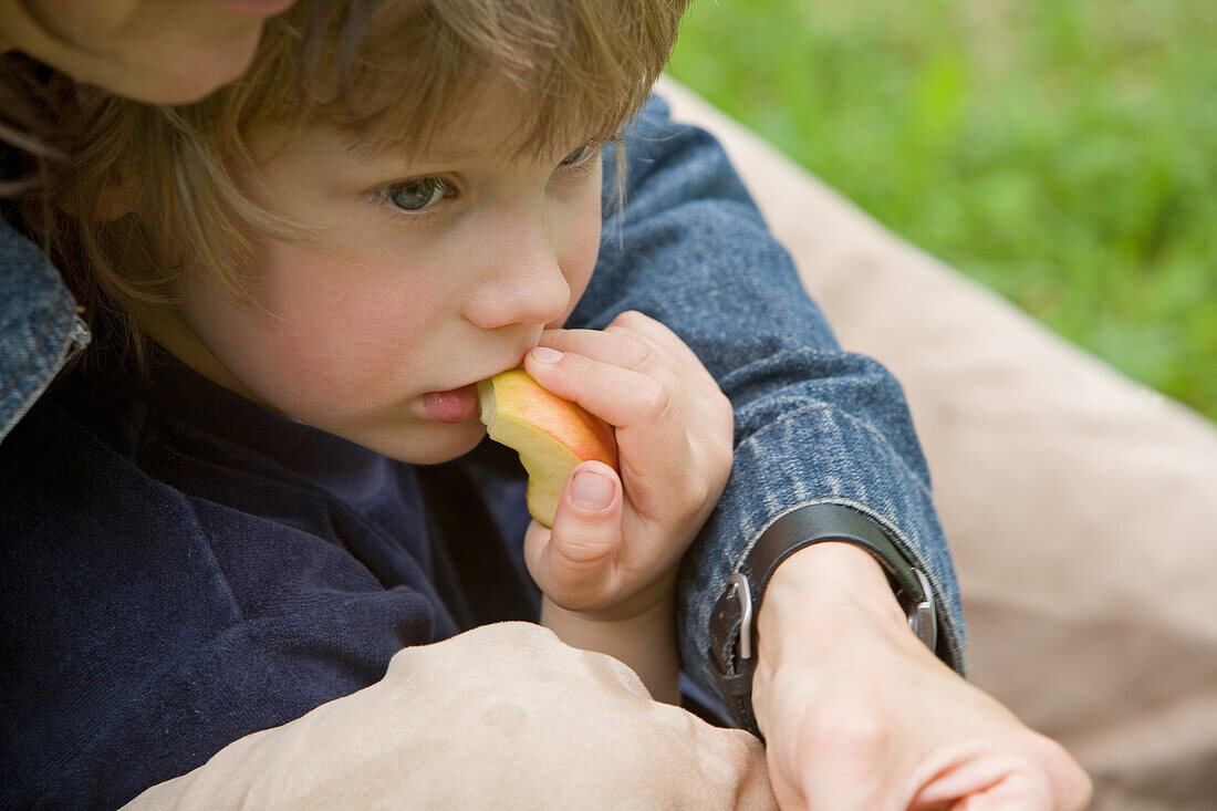 Woman embracing boy eating an apple, MR