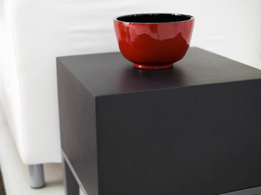 Shiny, red ceramic bowl on a square side table