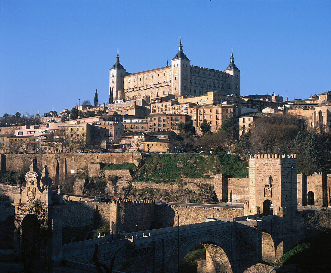Alcántara bridge and Alcázar fortress dominating the city in background. Toledo. Spain