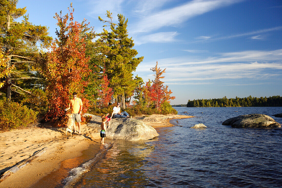 Family on a beach on Lake Millinocket in autumn, Maine, ,USA