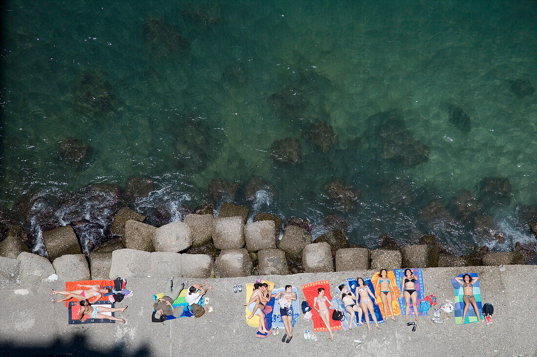Junge Menschen beim Sonnenbaden am Strand von Sorrent, Kampanien, Italien, Europa