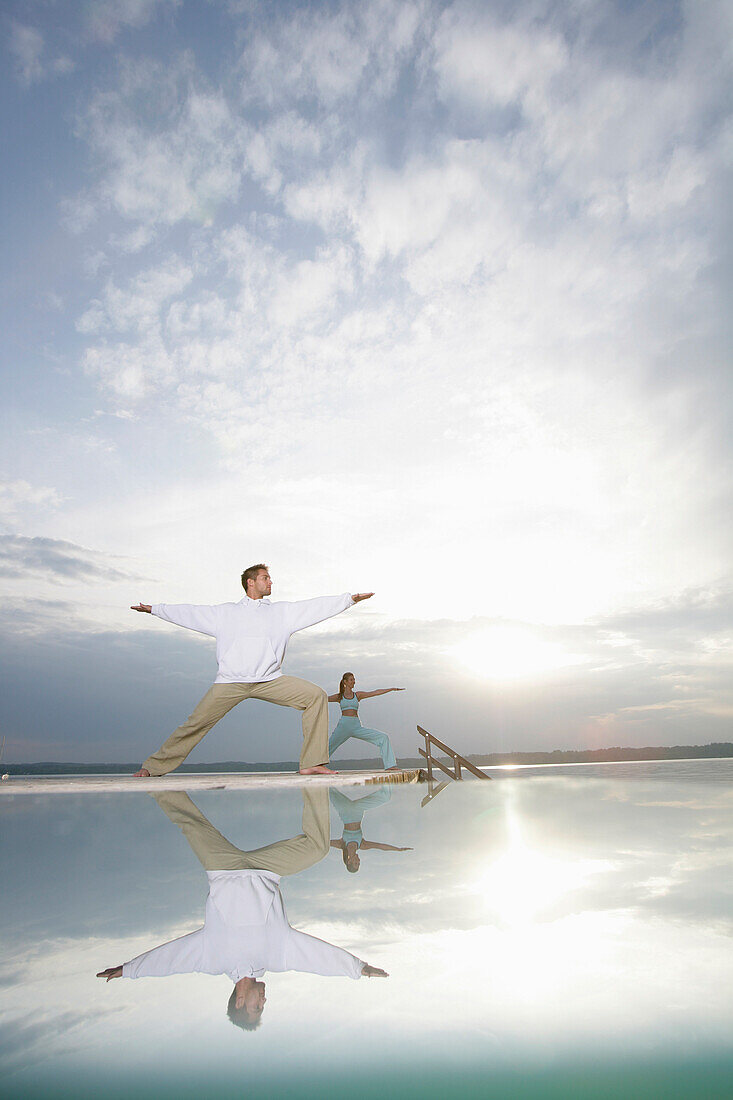 Couple practising yoga at Lake Starnberger, Muensing, Bavaria, Germany, MR