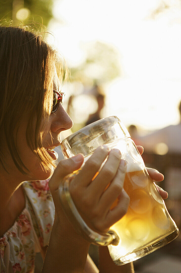 Mid adult woman drinking a glass of beer, beergarden Buchscharn, Muensing, Lake Starnberg, Bavaria, Germany, MR